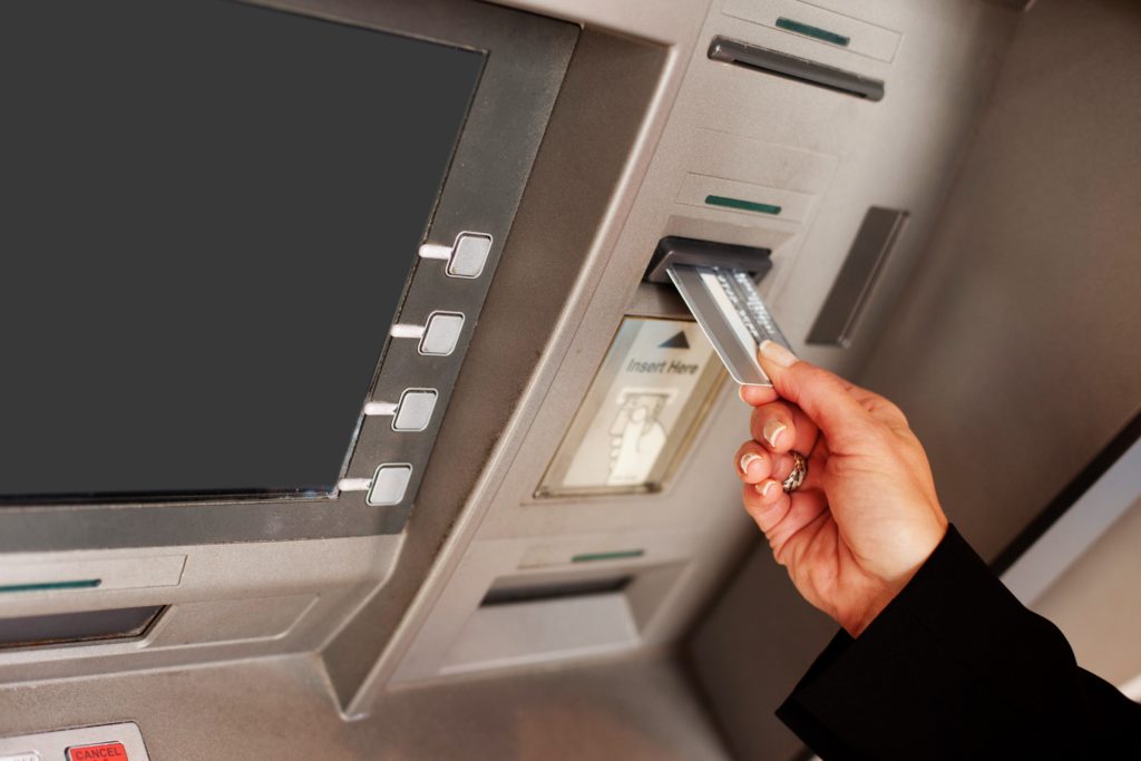 ATM の銀行カードを挿入する女性の手